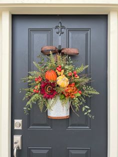 a front door decorated with fall flowers and pumpkins, greenery and other foliage