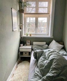 a bed sitting under a window next to a small table with a potted plant on it