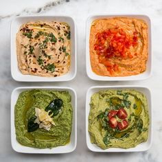 four small white bowls filled with different types of hummus and guacamole