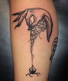 a woman's leg with a spider web tattoo on it and her hand holding the net