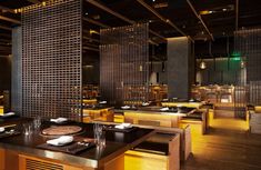 an empty restaurant with wooden tables and yellow lighting on the walls, along with place settings