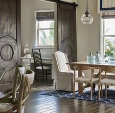 a dining room table and chairs in front of two windows with wood trimmings