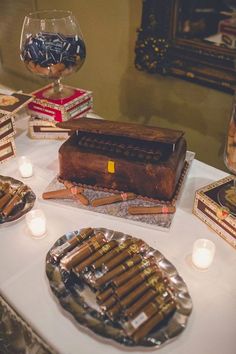 a table topped with lots of cigars next to candles and plates on top of it