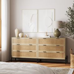 a bedroom scene with focus on the dresser and bed sideboard that has two framed pictures above it