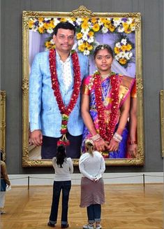 a man and woman standing in front of a painting with flowers on it's head