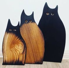 three black cats standing next to each other on top of a wooden table with eyes