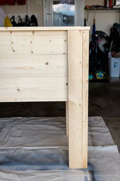 a wooden bed frame sitting on top of a sheet of paper in a room filled with tools