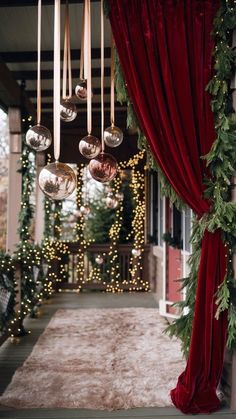 christmas decorations hanging from the side of a building with red curtains and lights on it