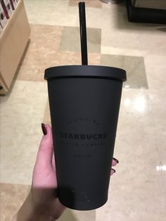 a woman holding up a starbucks cup with a straw in it