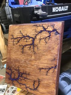 a piece of wood that has been painted with blue and purple paint on it, sitting next to a toolbox