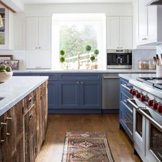 a kitchen with blue cabinets and white counter tops, an area rug on the floor