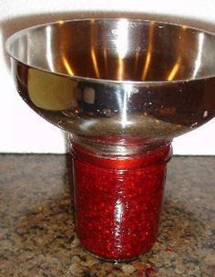 a metal bowl sitting on top of a counter next to a jar filled with red liquid