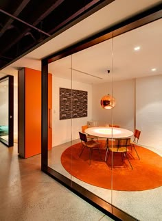 a glass walled dining room with an orange rug on the floor