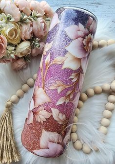 a close up of a cup on a table with flowers in the background and beads around it