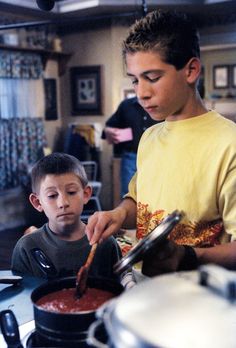 two young boys are cooking in the kitchen