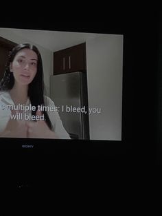 a tv screen showing a woman talking to someone in the kitchen with her hand on her chest