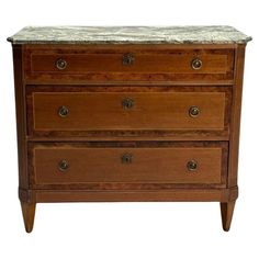 an old wooden dresser with marble top on it's sides and drawers in the middle