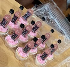 cupcakes with pink frosting and black numbers on them sitting in a plastic container