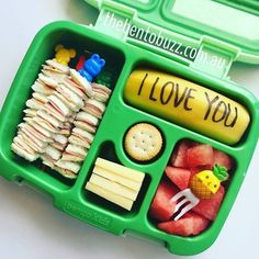 a green lunch box filled with fruit and veggies on top of a white table