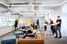 an office with people sitting at tables and standing in front of the projector screen