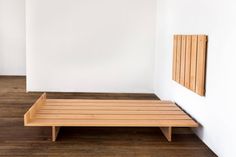 a wooden bench sitting on top of a hard wood floor next to a white wall