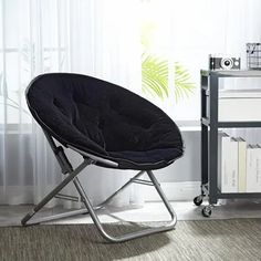 a black chair sitting on top of a carpeted floor next to a book shelf