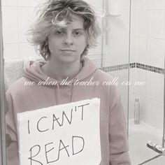 a young man holding a sign that says i can't read in front of him