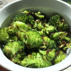 a white bowl filled with green broccoli on top of a window sill