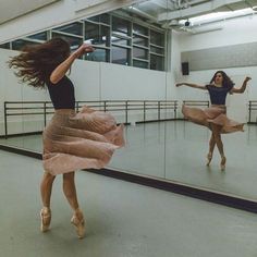 two women are dancing in front of a mirror while another woman is standing behind them