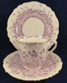 an antique tea cup and saucer with purple flowers