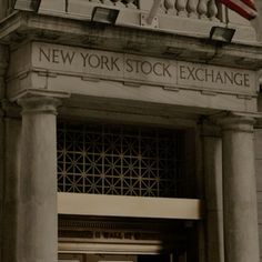 the new york stock exchange building entrance with an american flag flying in the wind above it