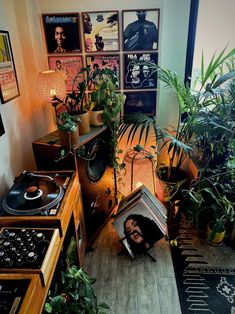 a room filled with lots of plants and records on top of a wooden table next to a window