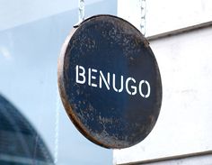 a sign hanging from the side of a building that says benugo on it