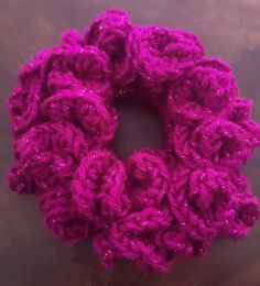 a purple crochet flower sitting on top of a table