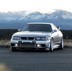 a silver car parked in front of a mountain