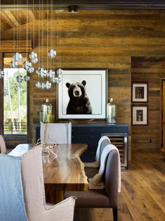 the dining room table is surrounded by white chairs and an art piece on the wall