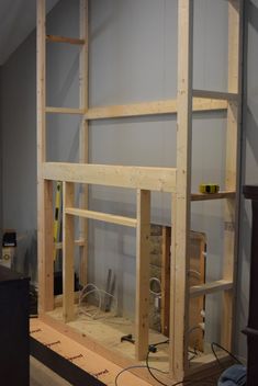 a room that is being built with some wood on the floor and shelves in it