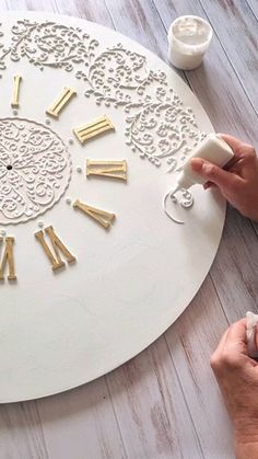 a person is working on a clock made out of wood and glues it to the wall