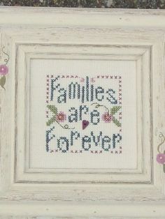 a cross - stitch picture frame with the words families are forever on it and flowers