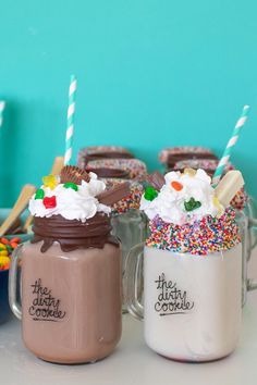 two mugs filled with chocolate frosting, sprinkles and marshmallows