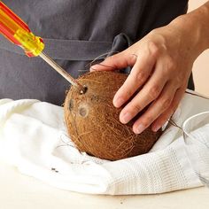 a person cutting into a coconut with a pair of scissors