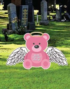 a pink teddy bear with angel wings on it's back in a cemetery yard