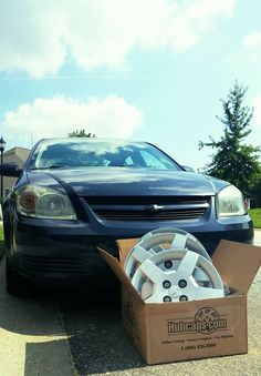 a blue car parked next to a cardboard box