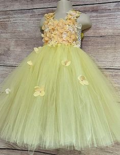 This adorable and beautiful dress is hand-made by Stella with full of love and affection and is perfect for your lovely girl for her birthday, being a flower girl, for the wedding party, being bridesmaid, for the christening, or any other special occasion. The dress features 6-inch-long soft crochet which is completely covered with beautiful yellow flowers that are scattered over the skirt and extending onto the shoulder straps. The matching satin shoulder straps are adjustable and tie into a bo Whimsical Tulle Tutu Dress For Garden Party, Cute Tulle Princess Dress For Garden Party, Spring Princess Dress With Flower Shape, Princess Style Fairy Dress With Floral Applique, Whimsical Tulle Princess Dress For Spring, Flower Shaped Summer Princess Dress For Party, Summer Party Princess Dress With Flower Shape, Whimsical Spring Tulle Princess Dress, Sweet Spring Princess Dress For Wedding