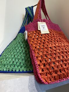 two crocheted purses sitting on top of each other, one with a price tag