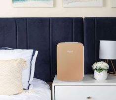 an air purifier sitting on top of a nightstand next to a bed