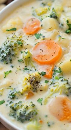 a white bowl filled with broccoli, carrots and dumpling next to crackers