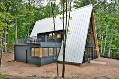 a house in the woods with a roof made out of metal shingles and windows