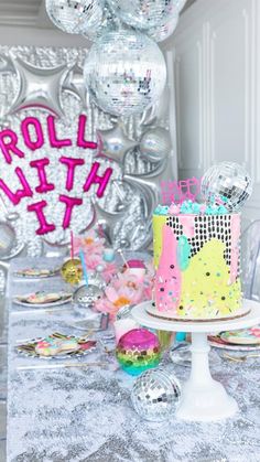 a table topped with a cake covered in confetti next to disco ball decorations