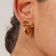 These super adorable bow earrings with a heart pendant drop is bound to turn heads. With every glance, these earrings radiate warmth and love, making them the perfect gift for someone special or a treat for yourself. These earrings come in gold and two-tone. Material: 18k gold plated on stainless steel 18k Gold Earrings, Heart Dangle Earrings, Mini Bows, Bow Earrings, Heart Studs, Pendant Design, Heart Earrings Studs, Girls Earrings, Stainless Steel Earrings